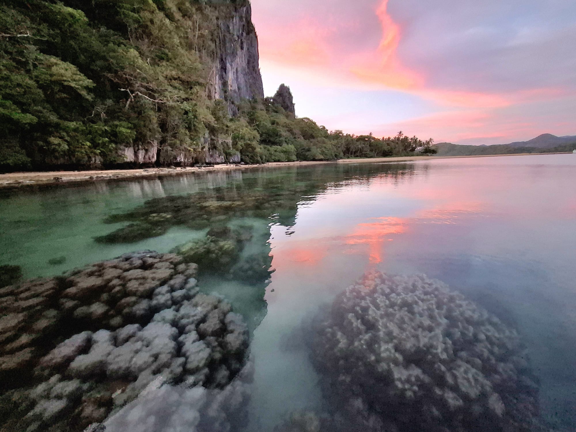 A dramatic sunset silhouette reflected across calm water